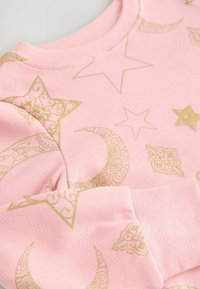 Rosa Sweatshirt mit goldenen Mustern von Sternen und Monden, aus weichem Stoff mit gerippten Bündchen. Elegantes und verspieltes Design.