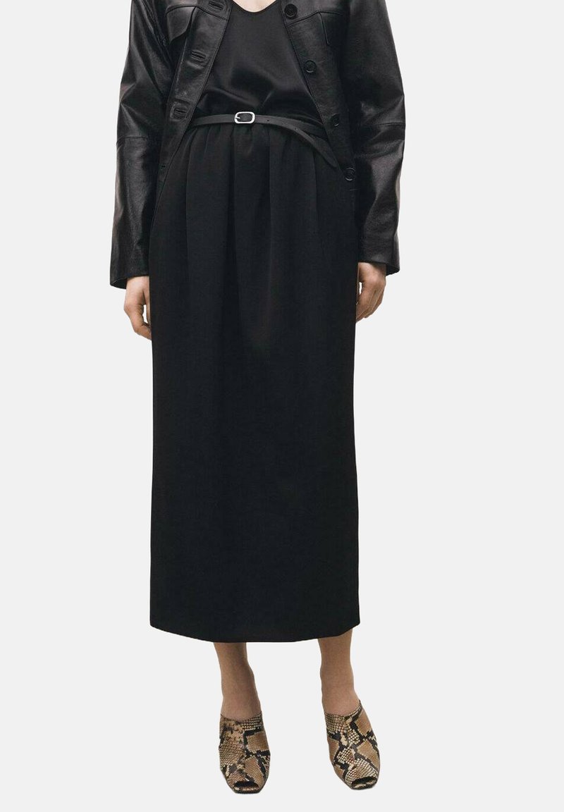 Black leather jacket over a black top and a long black skirt. The outfit features a belt and snakeskin-printed shoes. Smooth textures evident.