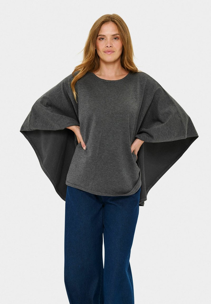 Tumši pelēks lielgabarīta tops ar plašām piedurknēm, izgatavots no mīksta auduma. Tam ir apaļa apkakle un relaksēta piegriezuma, apvienots ar zilām plašām biksēm.