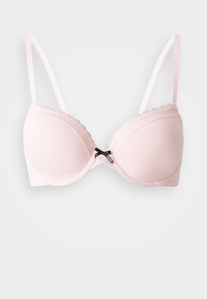 Soutien-gorge rembourré rose clair avec des bordures en dentelle, bretelles réglables et un accent central en nœud noir. Tissu lisse avec un design de coupe arrondie.