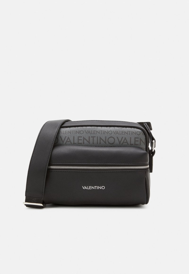 Black leather crossbody bag with zip closure, embossed logo on top, and adjustable strap. Smooth texture, compact rectangular shape.