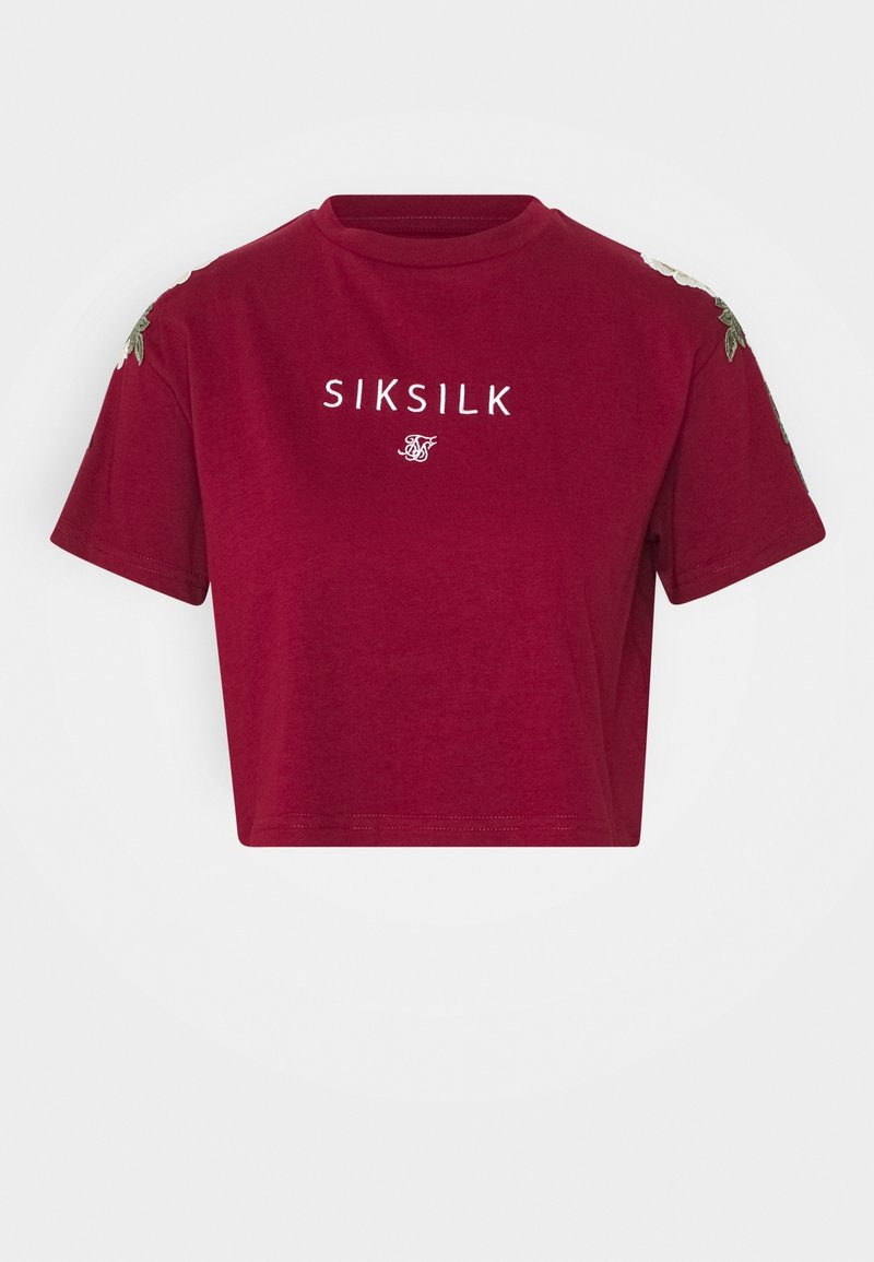 Vínový zkrácený tričko s krátkým rukávem s bílým nápisem "SIKSILK" a květinovou výšivkou na rukávech na bílém pozadí.