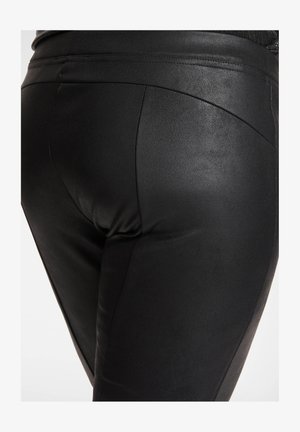Czarne legginsy z imitacji skóry o gładkiej fakturze i dopasowanym kroju. Charakteryzują się wysokim pasem oraz subtelnymi przeszyciami.