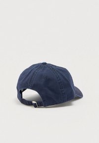 Βαμβακερό μπλε σκούρο καπέλο μπέιζμπολ με ρυθμιζόμενο μεταλλικό πόρπη στο πίσω μέρος, εμφανιζόμενο σε ανοιχτό ουδέτερο φόντο.