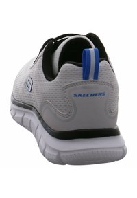 Herren Sport shoes von Skechers, mit grauem Stoffobermaterial, schwarzen Akzenten, blauer Fersenlasche, weicher gepolsterter Sohle und strukturiertem Mesh-Design.