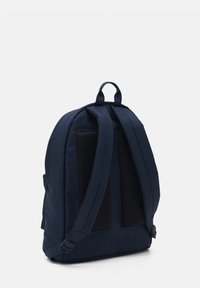 Sac à dos bleu marine avec un dos rembourré en mesh, des bretelles réglables, une poignée supérieure et des poches latérales pour le rangement. Matière en toile texturée.