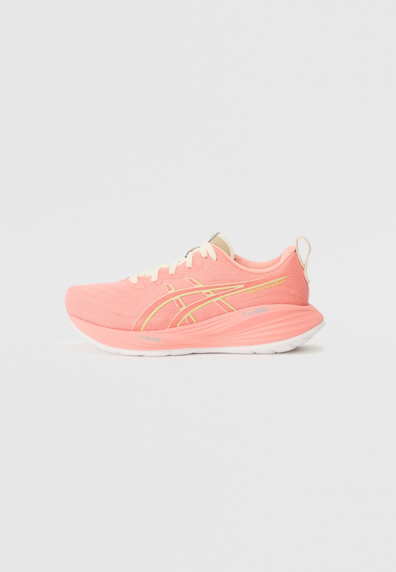 Chaussure de sport rose avec une tige en maille texturée, lacets crème, détails jaunes et semelle blanche, présentant un bout arrondi et une languette.