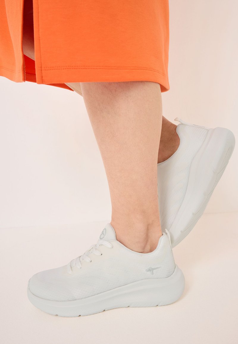 Lightweight, white athletic shoes with a textured, breathable upper, featuring a cushioned sole and minimal lace design.