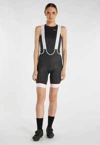 Shorts da ciclismo neri con bretelle bianche regolabili, dettagli rosa alle aperture delle gambe, progettati per comfort e performance con una forma aderente.