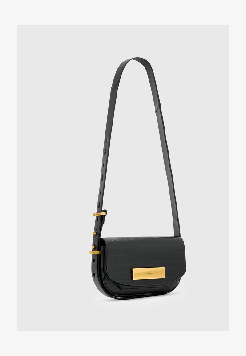 Čierna taška cez telo z imitácie krokodílej kože s akcentmi zlatého hardvéru a plochým predným vekom. Nastaviteľný popruh s viacerými dierkami.