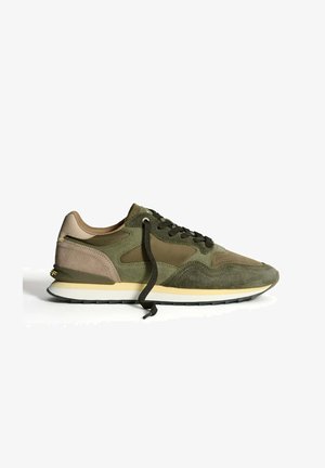 Grønne og beige ruskindsneakers med uknappede sorte snørebånd, gul og hvid mellemsål og tekstureret sål på hvid baggrund.