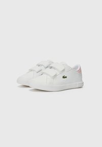 Weiße Lederschuhe mit zwei Klettverschlüssen, glatter Oberfläche, runder Zehenform und einem pinken Akzent an der Ferse. Mit einem grünen Logo.