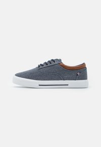 Baskets en toile de couleur bleu foncé avec des accents en cuir marron, bout rond, design à lacets, semelle en caoutchouc blanche et détails en stripe navy.