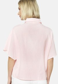 Camicetta rosa chiaro con colletto e maniche corte e ampia, caratterizzata da una sottile trama a righe e un fit rilassato.