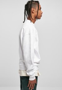 Hvid sweatshirt med ribbede manchetter og kant. Let oversized pasform, med rund halsudskæring og sænkede skuldersømme.
