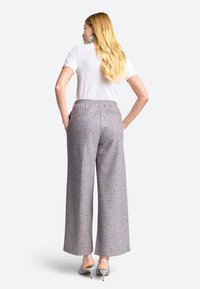 Wide-legged, patterned trousers in light blue, gray, and cream fabric, featuring an elastic waistband and side pockets.