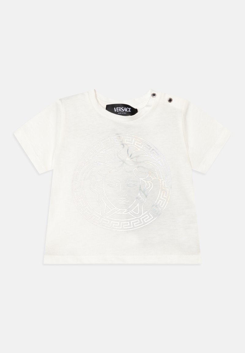 Camiseta de algodón blanca de manga corta con un brillante emblema de Medusa y diseño de clave griega, con dos acentos de botones a presión en el hombro.