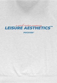 Felpa grigio chiaro con una texture morbida. Il testo in grassetto, blu e rosso, recita "LEISURE AESTHETICS" con "un'azienda di couture per divani" sopra.