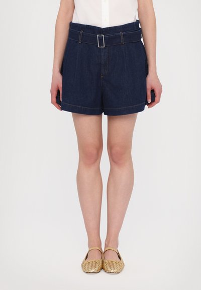 Donkerblauwe denim shorts met een hoge taille en riemontwerp, voorzien van plooien en contrasterende stiksels. Draagt men met geweven gouden flats.