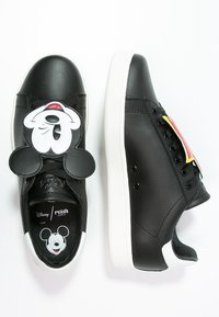 Svarta lädersneakers med vita sulor, med en design av Mickey Mouse-ansiktet på tungan och en annan på innersulan. Snörningsdetaljer.