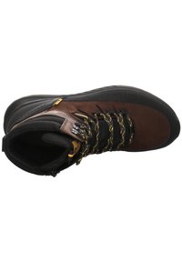 Botte de randonnée marron et noire avec une tige texturée, des accents jaunes et des lacets noirs. Dotée d'une semelle en caoutchouc robuste pour la durabilité.