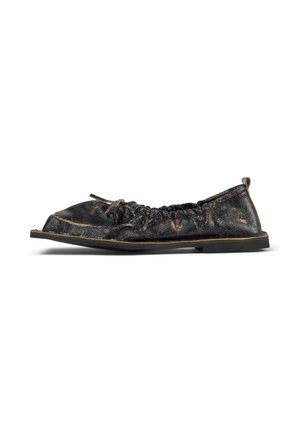 Zapato plano de cuero negro desgastado con laterales elásticos, un pequeño lazo en la parte superior y una suela de goma plana, mostrado de lado.