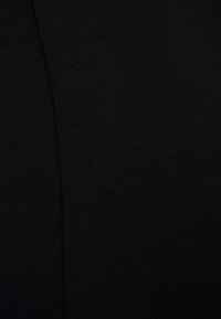 Czarna tkanina o drobnej fakturze, charakteryzująca się gładką powierzchnią i subtelnym połyskiem, podkreślona detalem w postaci zakrzywionego szwu.