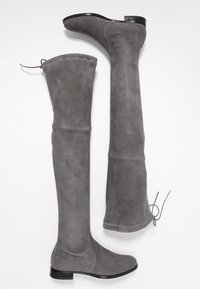 Botas grises hasta la rodilla hechas de suave gamuza, con una punta redonda y tacón plano, y un detalle de cordón en la parte superior del caña.