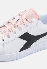 Sneaker bianco con accenti neri, lacci rosa e morbida fodera in tessuto. Presenta una tomaia in pelle liscia e una suola in gomma testurizzata.