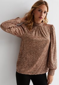 Rose gold sequined top with a high gathered neck, long puffed sleeves, and ribbed cuffs, featuring a soft texture and fitted silhouette.