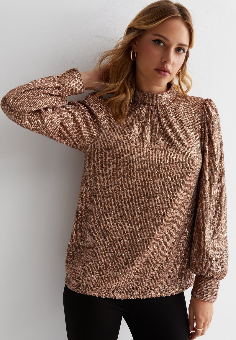 Rose gold sequined top with a high gathered neck, long puffed sleeves, and ribbed cuffs, featuring a soft texture and fitted silhouette.