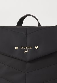 Zwarte, gewatteerde rugzak van nylon, met een gouden logo en hartaccenten, een bovenhandvat en scherpe geometrische stikdetails.