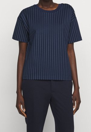 Dark-skinned person wearing a navy blue short-sleeve top with white pinstripes and matching navy pants, standing against a white background.