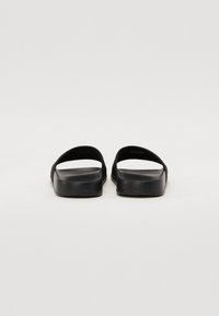 Sorte svart sandaler med to brede stropper, en flat såle og lett polstring. Glatt tekstur med minimale design detaljer.