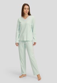 Pijamas de color verde menta claro, fabricados con tejido suave, que presentan un escote en forma de v con borde de encaje y un sutil patrón en zigzag en la parte superior y los pantalones.