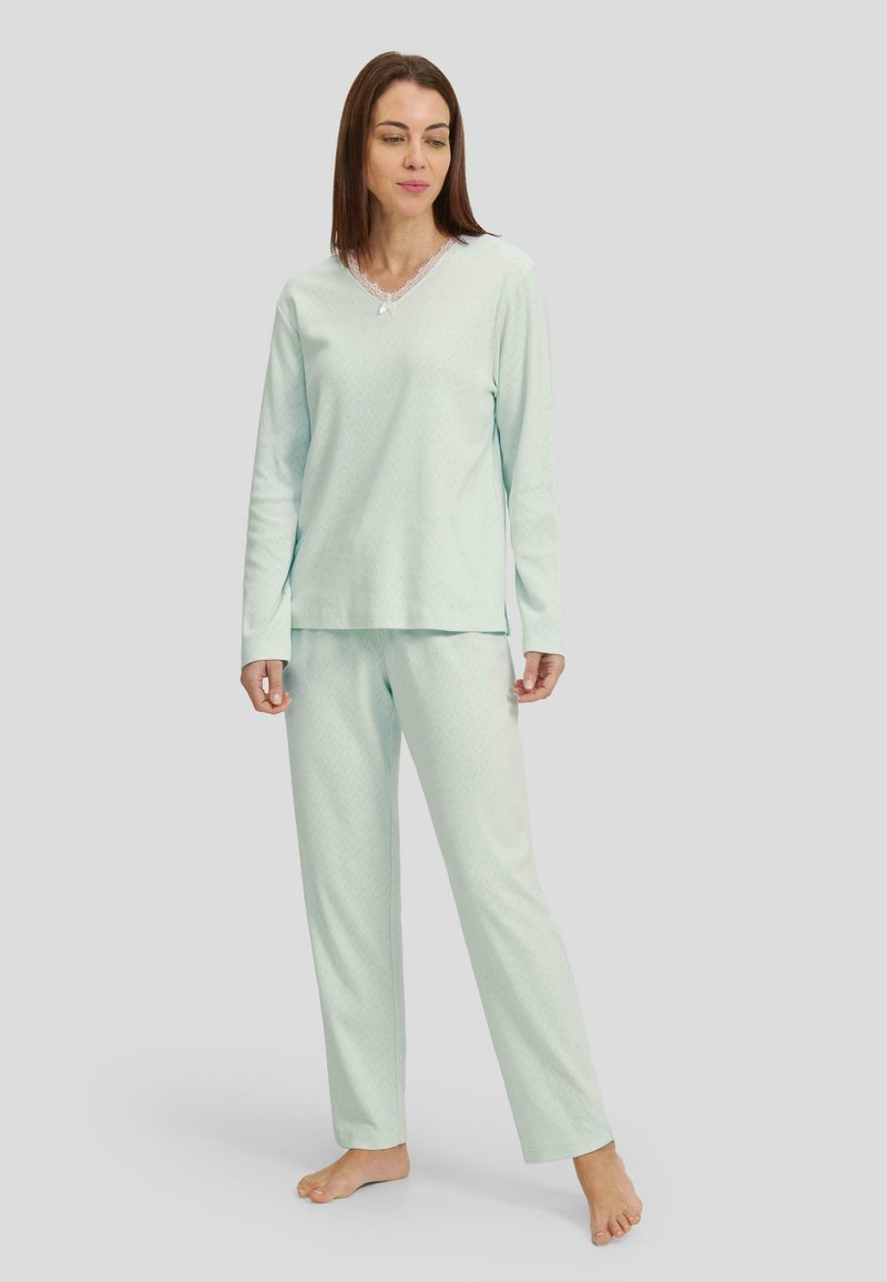 Pijamas de color verde menta claro, fabricados con tejido suave, que presentan un escote en forma de v con borde de encaje y un sutil patrón en zigzag en la parte superior y los pantalones.