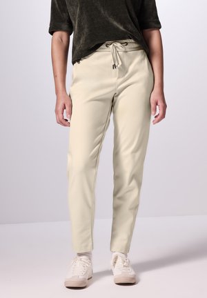 Cremfarbene Dehnhose mit elastischem Bund und Kordelzug. Hergestellt aus weichem Material mit einem taillierten Bein Design.