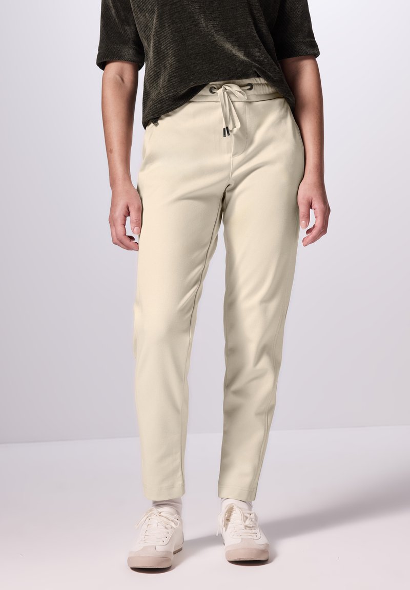 Crème kleurige pull-on broek met een elastische tailleband en trekkoord. Gemaakt van zachte stof met een taps toelopend ontwerp.