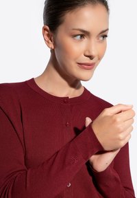 Cardigan bordeaux con scollatura tonda, polsini a costine, chiusura con bottoni e dettaglio ricamato sulla manica, realizzato in morbido tessuto a maglia.