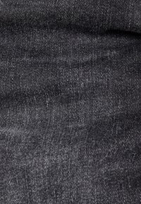 Tela de mezclilla gris oscuro con una textura suave, que presenta un clásico tejido de sarga y sutiles variaciones de color a lo largo.