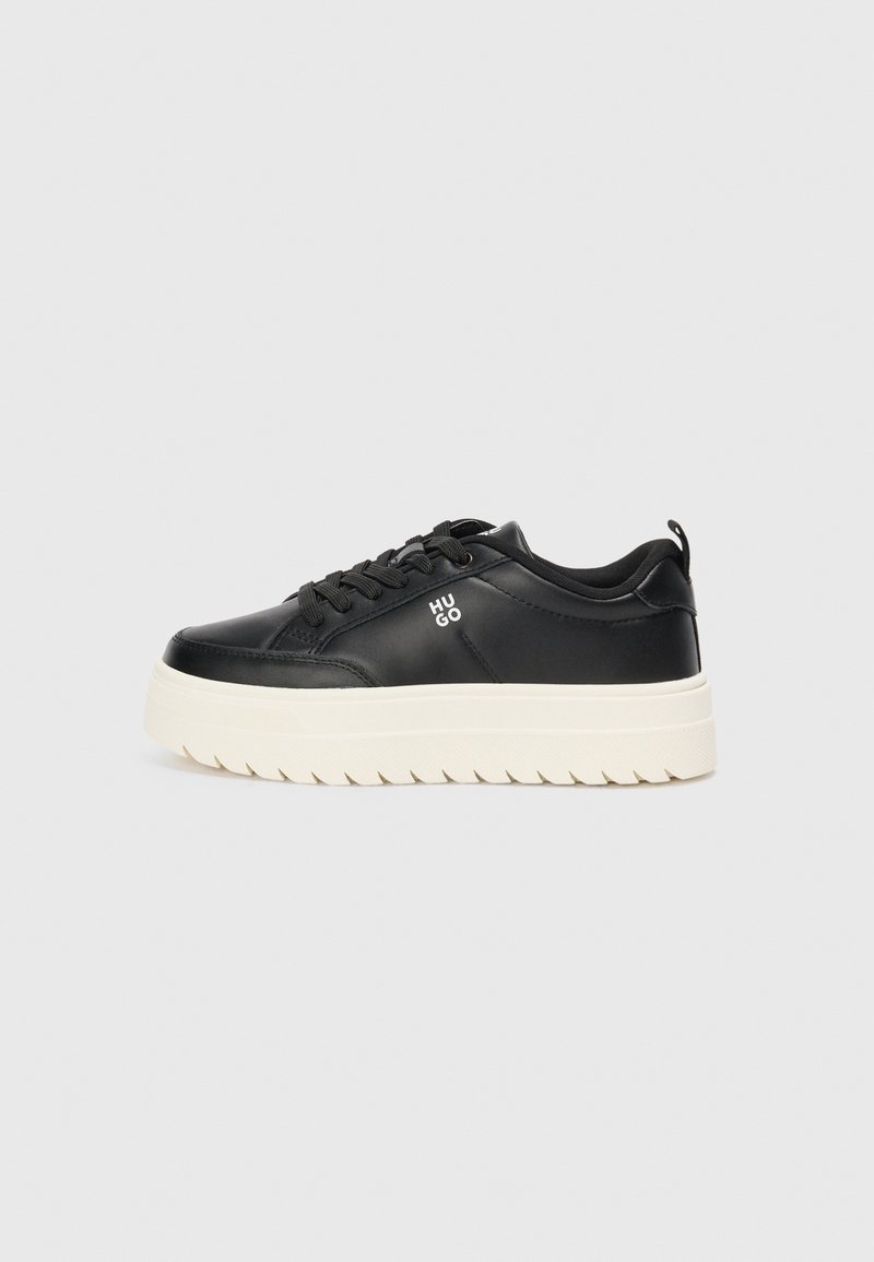 Zapatilla negra de cuero con suela blanca gruesa, punta redonda y cordones planos; presenta el logo "HUGO" en el lateral y una suela texturizada para mayor agarre.