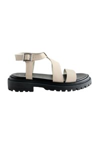 Beige læder sandal med krydset remme, justerbar ankelspænde og tyk sort gummisål med slidmønster.