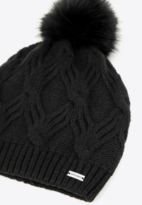 Czarna dzianinowa czapka typu beanie z teksturowanym wzorem warkocza, ozdobiona puszystym pomponem na czubku oraz małą białą metką z napisem "WITTCHEN" na krawędzi.