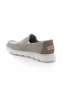 Scarpa slip-on grigia con tomaia in tessuto testurizzato, dettagli marroni e suola bianca maculata. Presenta un design semplice con pannelli laterali elasticizzati.