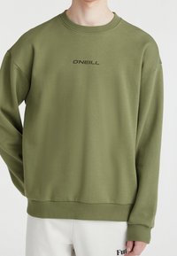 Oliwkowy sweter z okrągłym dekoltem i opadającymi ramionami. W przodzie znajduje się ciemny nadruk z logo "O'NEILL". Miękka struktura.