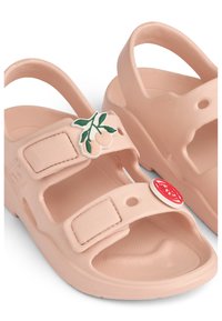 Παιδικά σανδάλια χρώματος ροδάκινου με ρυθμιζόμενους ιμάντες, στρογγυλές διακοσμήσεις με θέμα φρούτα σε κόκκινο και πράσινο χρώμα, και υφή στη σόλα.