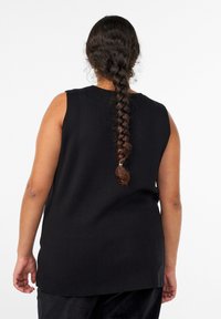 Čierny top bez rukávov s okrúhlym výstrihom, textúrovanou látkou a rovnostranným strihom. Na chrbte je dlhý zapletený účes.