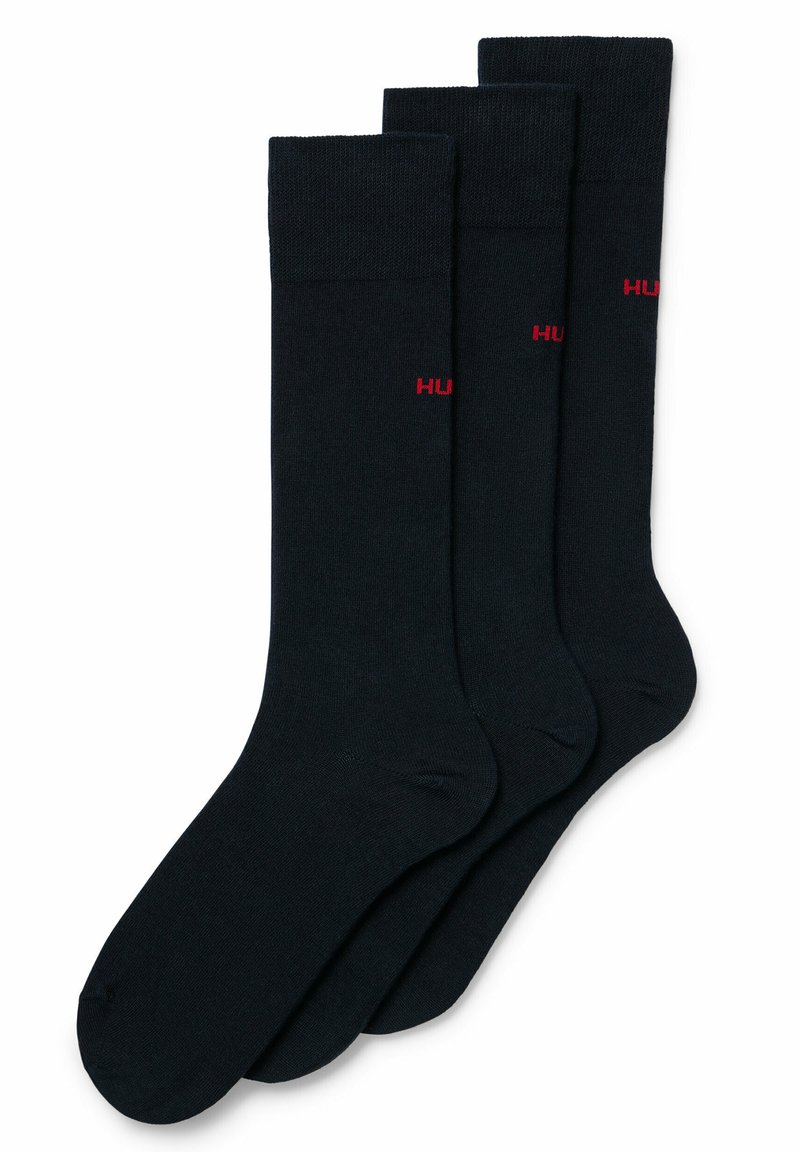 Schwarze Baumwollsocken im Dreierpack, mit einem gerippten Bündchen und einem kleinen roten "HUGO"-Logo an der Seite. Glatte Textur und klassisches Design.