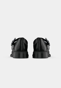 Black leather shoes with a smooth texture, low heel, and a decorative buckle on the side. Simple, streamlined design.