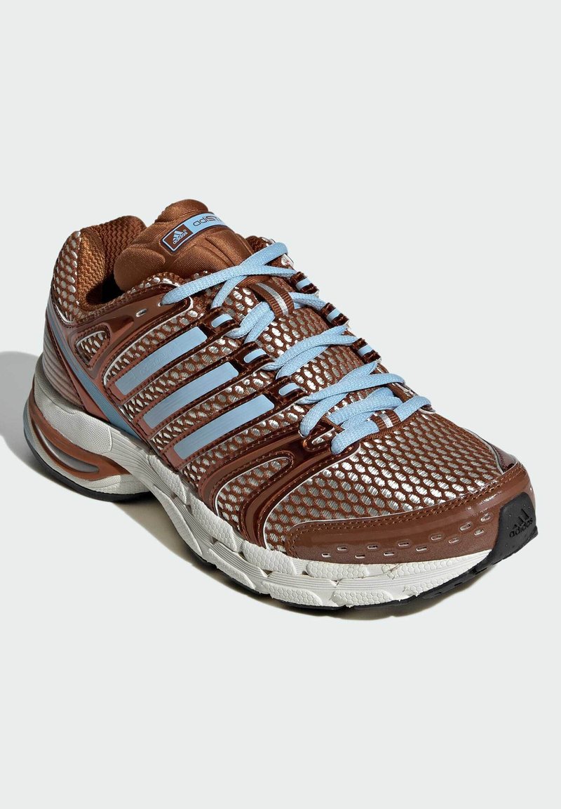 Chaussure de sport marron et bleu clair avec dessus en mesh et cuir synthétique, semelle en caoutchouc, design incurvé, et logo de marque visible sur la languette.